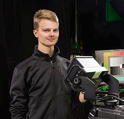 student standing in front of camera equipment in a film studio