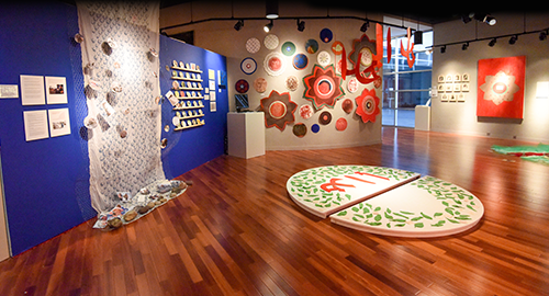 Contemporary art gallery interior with textiles on a deep-blue wall and a circular painted floor installation