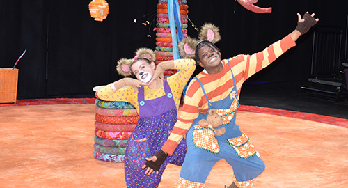 a girl dressed as a mouse and a boy dressed as a mouse on a stage in colorful costumes