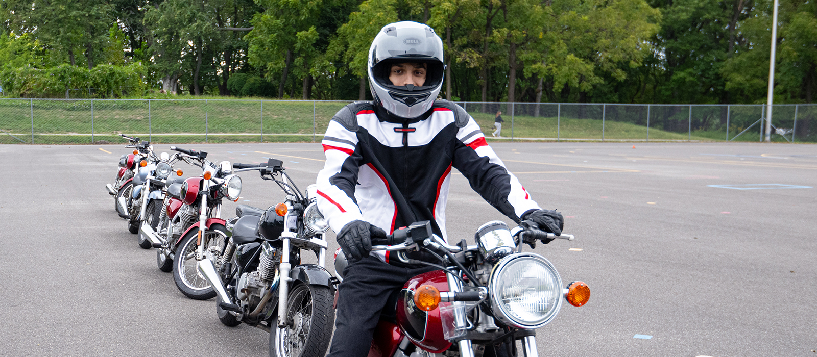 A Rider School participant on a motorcycle, with several motorcycles behind him on the course.