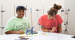 KOC teacher and student wearing a coral and mint green tshirt that says 'Kids on Campus' on the front.