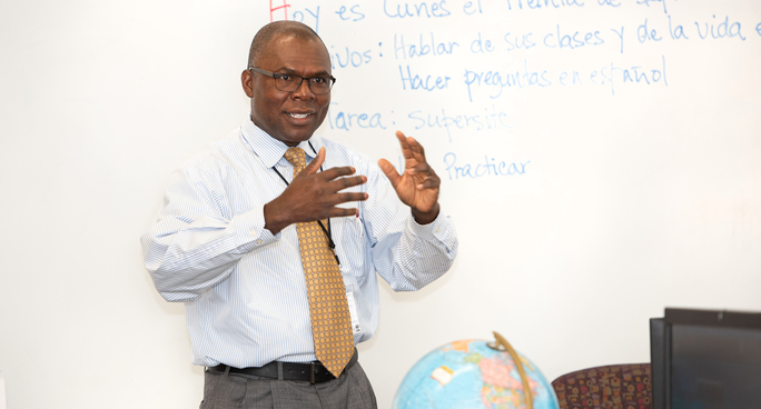 Instructor teaching in a classroom with written language examples on a whiteboard