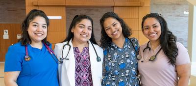 the Rivera sister pose for a photo wearing their nursing scrubs.