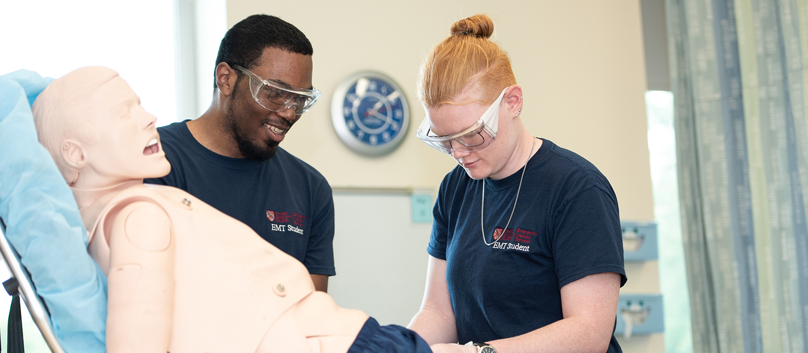 Two EMT students working over a dummy on a gurney