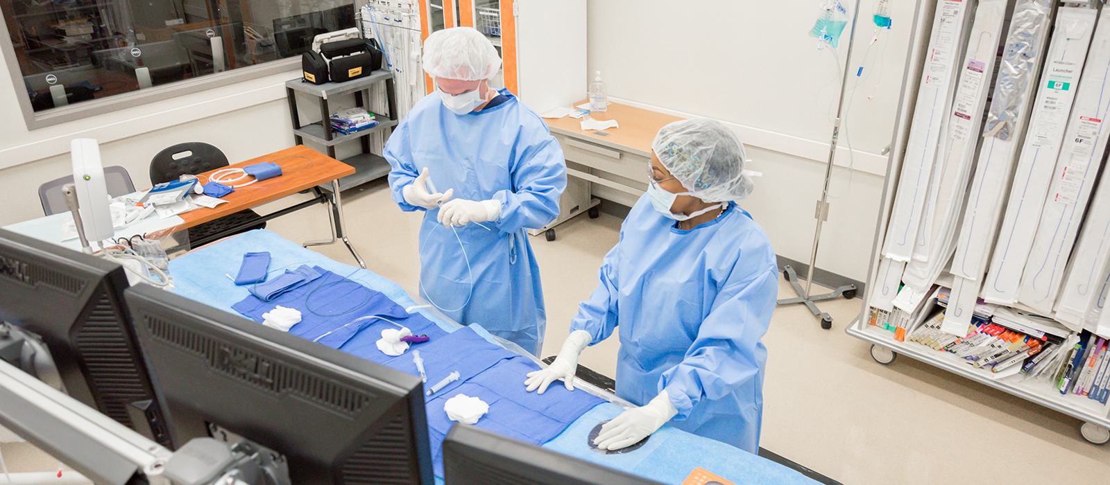 Two people in surgical gear using medical equipment