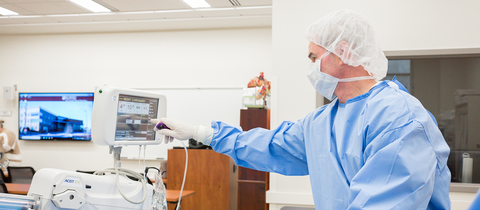 Man in surgical gear using a piece of medical equipment