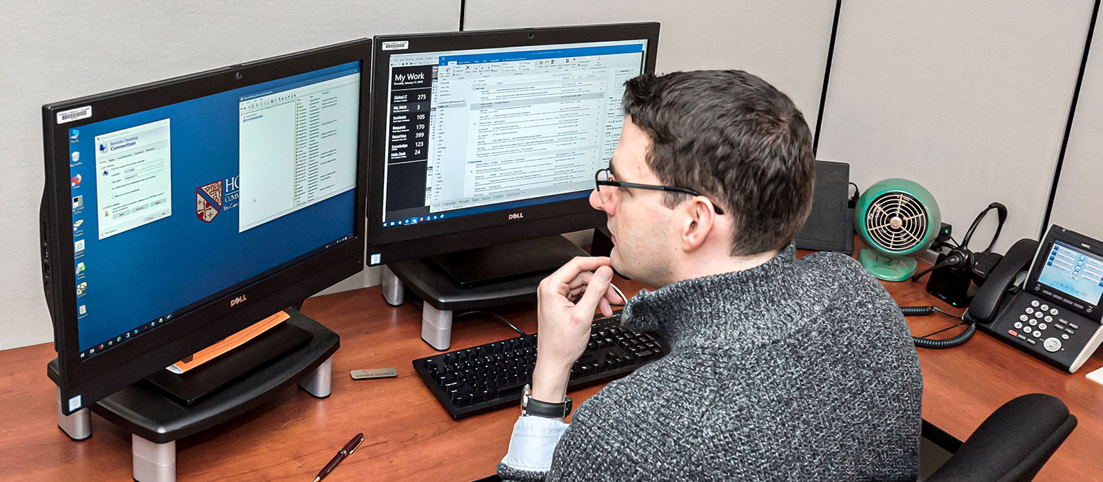 A person sitting and working in front of two computer monitors