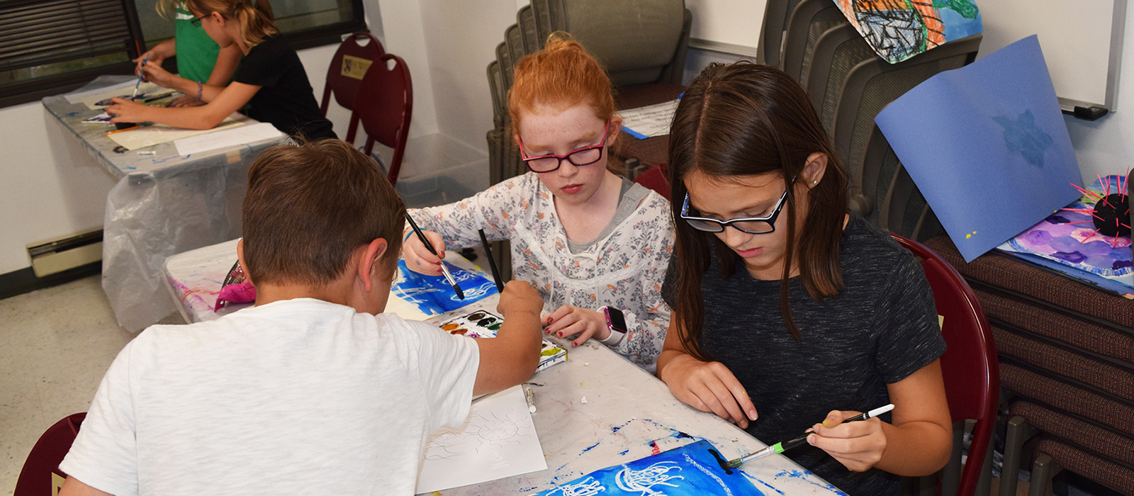 Young students sitting at tables doing crafts
